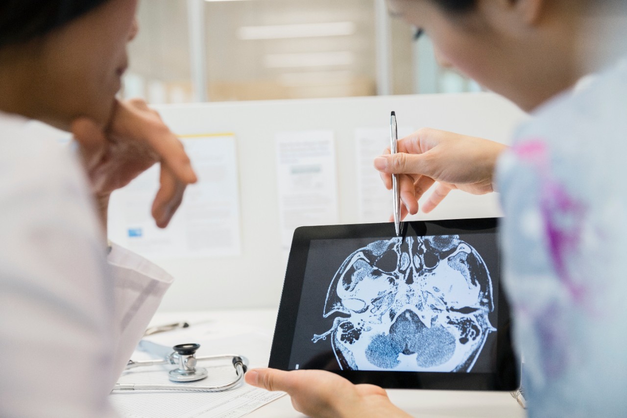 Doctor and nurse examining CT scan on tablet